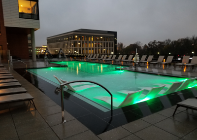 1,568 square foot heated swimming pool at nighttime. Water glowing bright green.