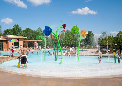Public event at Woodlawn commercial inground swimming pool with multicolored flower water features.